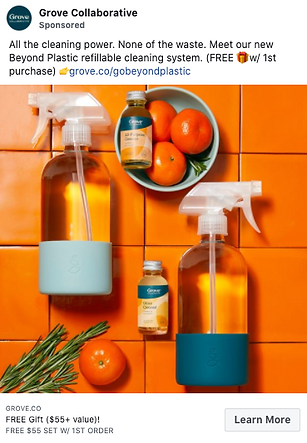 Two spray bottles, two bottles of cleaning concentrate, and several mandarins are arranged on an orange tiled surface. Text promotes a refillable cleaning system and a free gift with purchase.