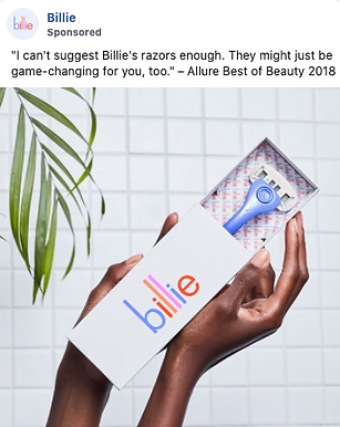 A person holds an open Billie razor box, displaying a blue razor inside; a green plant is in the background.