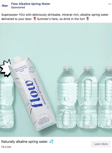 A carton of Flow alkaline spring water is displayed next to three clear plastic water bottles on a light blue background.