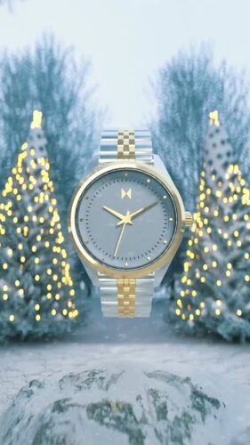 A silver and gold wristwatch is centered in front of two outdoor, decorated Christmas trees with white lights in a snowy setting.