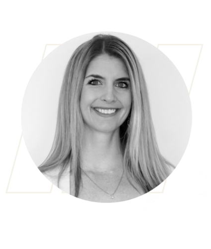 Black and white portrait of a smiling woman with long straight hair, wearing a necklace and a light-colored top, set against a plain background.
